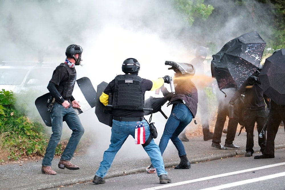 Members of the far-right group Proud Boys and anti-fascist protesters spray bear mace at each other during clashes between the politically opposed groups in Portland, Oregon, August 22, 2021 (AP)