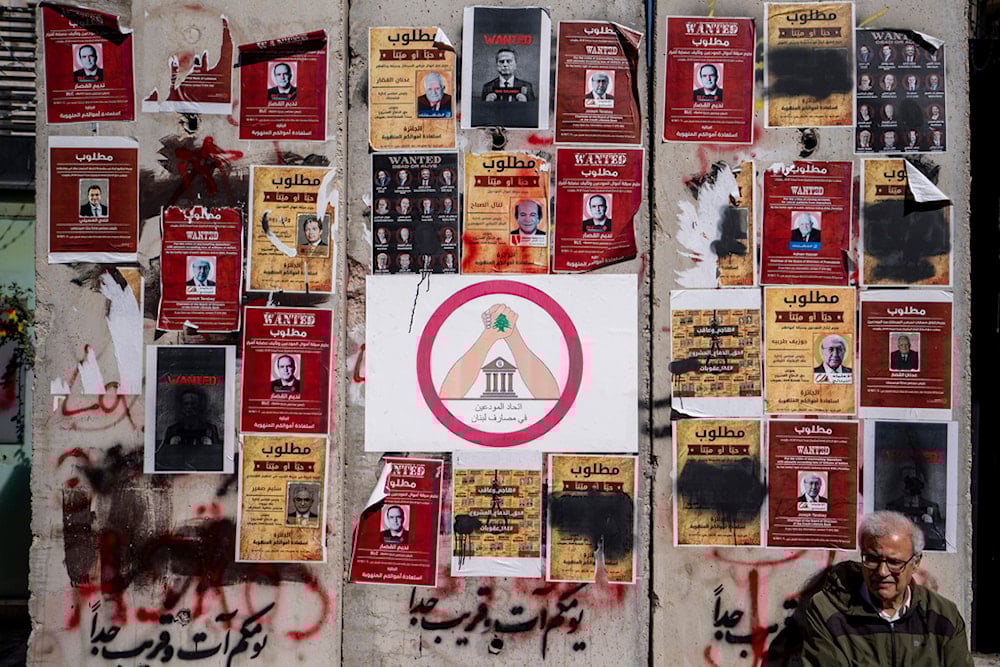 A depositor protester sits in front of a barrier wall that is set outside the Lebanese Central Bank, with full of Mock 