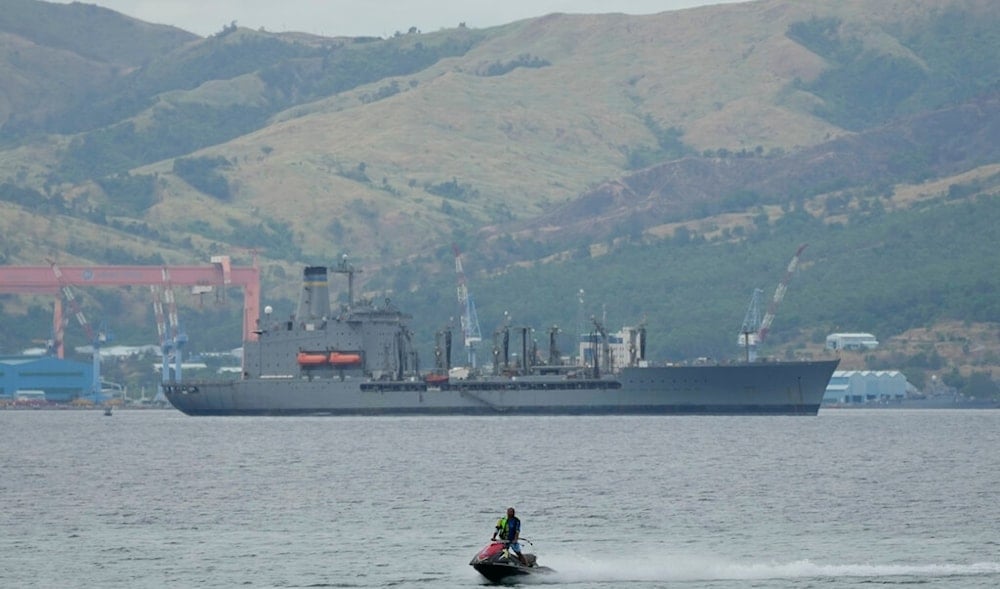 A man on a jetski passes by the USNS Big Horn American supply ship docked near a shipyard in what used to be the US's largest overseas naval base at the Subic Bay Freeport Zone, northwest of Manila, Philippines, Feb. 6, 2023. (AP)