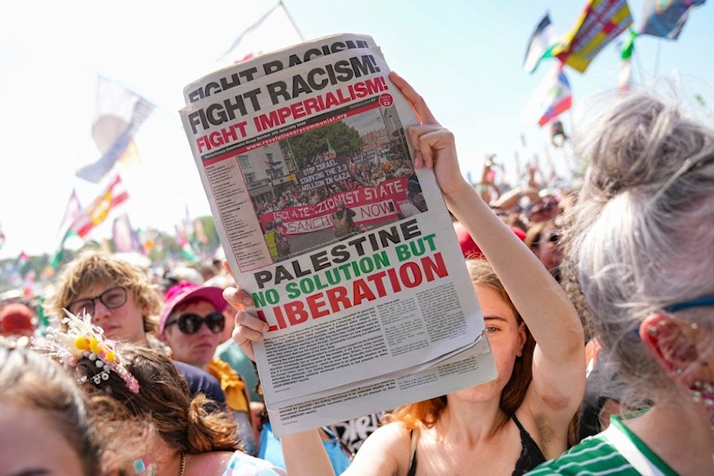 A festivalgoer holds a newspaper that reads 