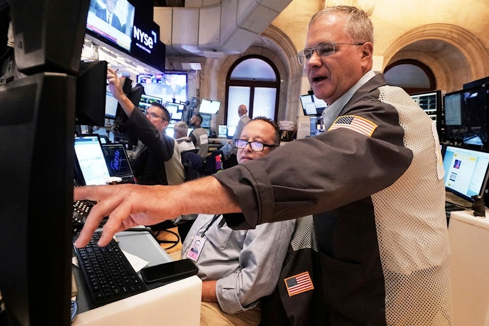 Traders Bryan Masseria, center, and Columb Lytle, right, works on the floor of the New York Stock Exchange, Monday, Aug. 18, 2025. (AP Photo/Richard Drew)