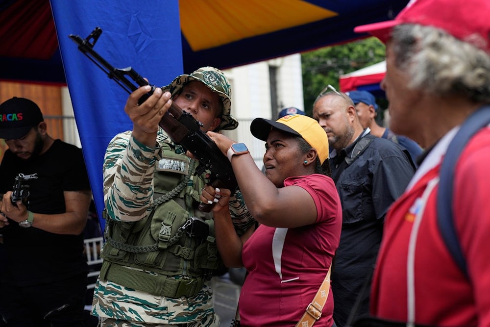A member of the Bolivarian National Militia shows a woman how to operate a weapon during military exercises in Caracas, Venezuela, Saturday, Sept. 20, 2025 (AP)
