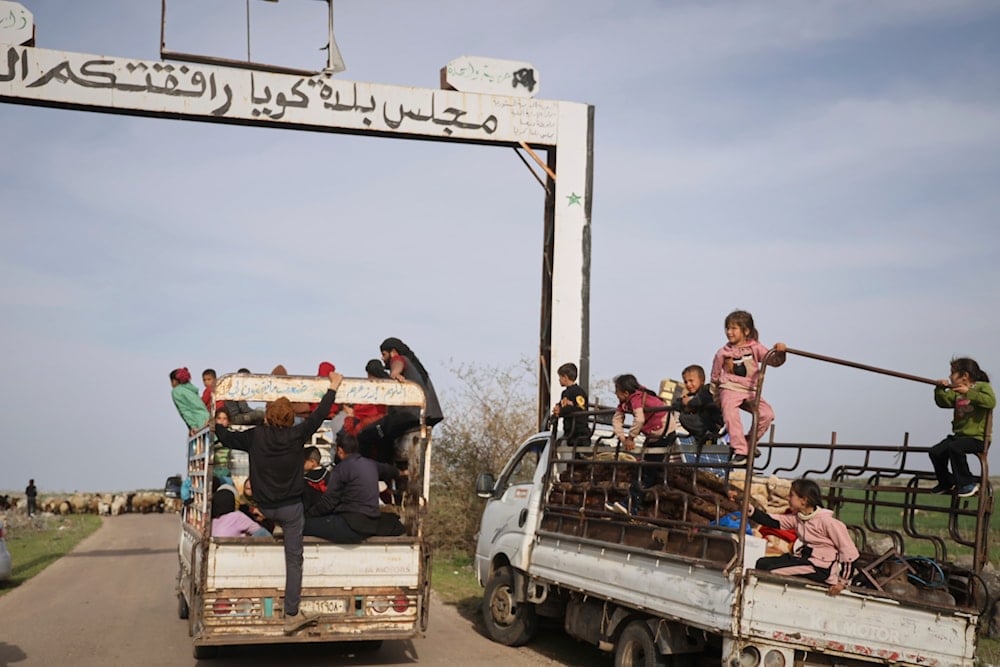 Local residents ride in the back of vans as they are evacuated due to fears of Israeli army incursions, on the outskirts of the village of Koya, southwestern Syria, Tuesday, March 25, 2025 (AP)