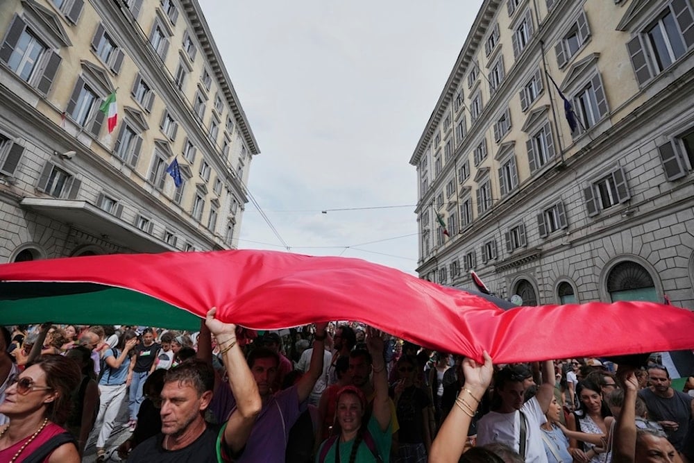 People hold a giant Palestinian flag as they participate in a demonstration part of a nationwide protest and general strike against the killings in Gaza, in Rome, Monday, September 22, 2025 (AP)