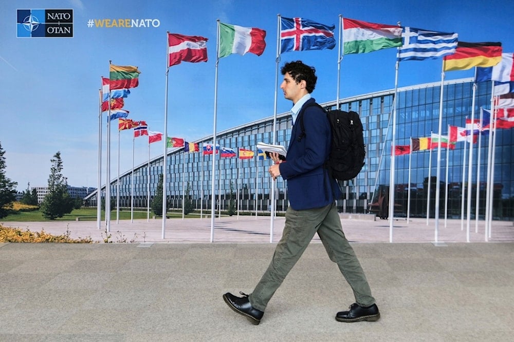 A man walks by a mural with flags of NATO member countries at NATO headquarters in Brussels, Tuesday, Sept. 23, 2025. (AP Photo/Virginia Mayo)