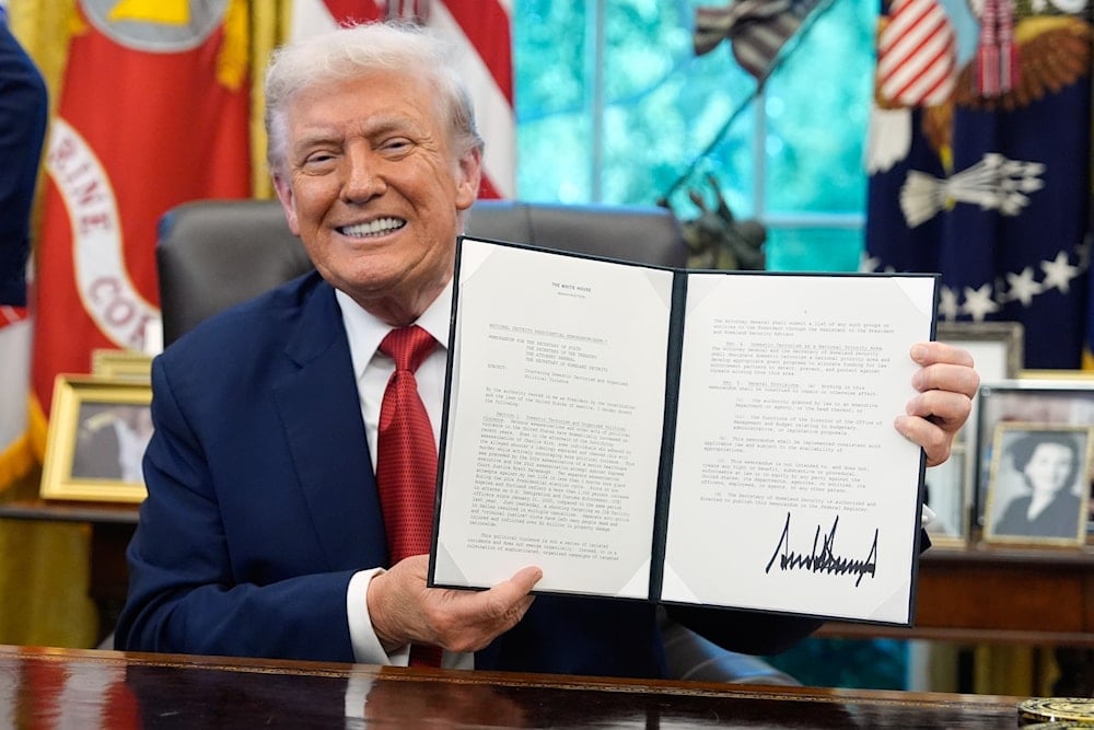 President Donald Trump holds a signed presidential memorandum on countering domestic terrorism and organized political violence, in the Oval Office at the White House, Thursday, Sept. 25, 2025, in Washington (AP)