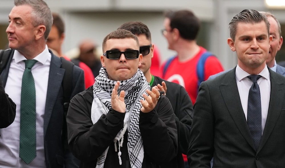 Liam Óg Ó hAnnaidh, aka Mo Chara, centre, a member of the Irish language band Kneecap, applauds as he leaves Woolwich Crown Court in London, Friday, Sept. 26, 2025. (AP)
