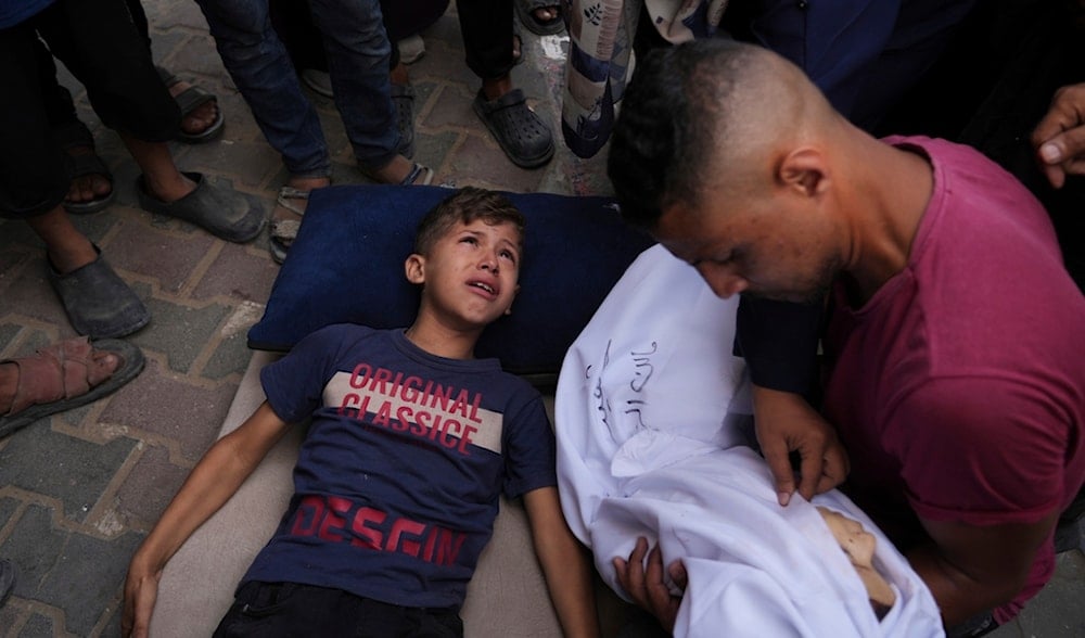 Omar Al-Zaqzouq, 7, mourns over the body of his 2-year-old brother Malek, who was killed in an Israeli strike, during his funeral outside Al-Aqsa Hospital in Deir al-Balah, in the central Gaza Strip, Monday, Sept. 22, 2025. (AP)
