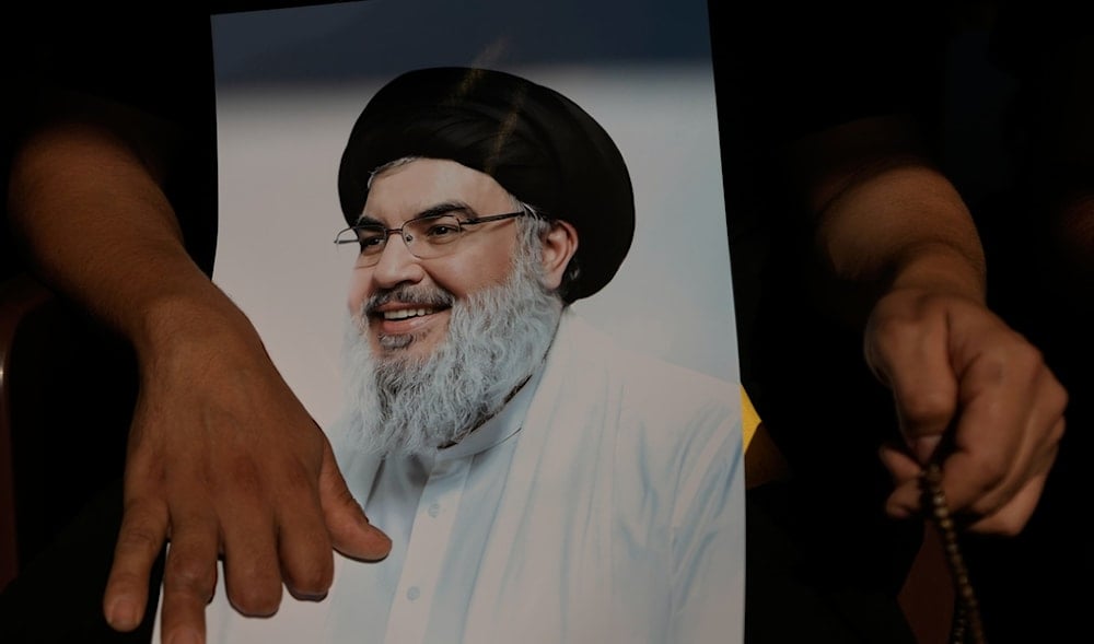 A Lebanese who lost several of his fingers during Sept. 17, 2024, pager attacks, holds a picture of Hezbollah leader Sayyed Hassan Nasrallah on the first anniversary of Nasrallah's assassination at his grave in Beirut, Lebanon, Sept. 27, 2025. (AP)