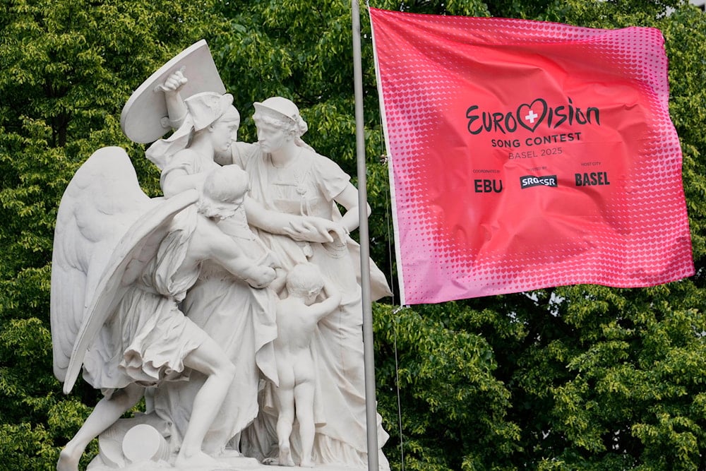 A Eurovision flag blows in the wind beside a memorial with Swiss national personification Helvetia at the start of the Eurovision Song Contest week in Basel, Switzerland, Monday, May 12, 2025 (AP)