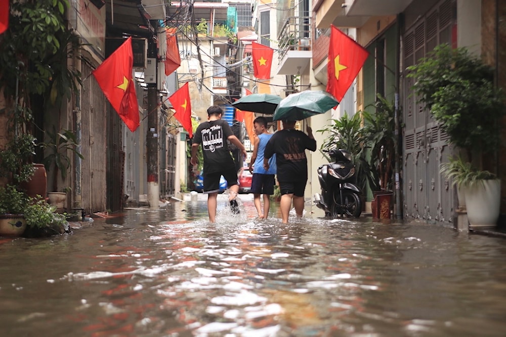 People wade through a flooded alley caused by Typhoon Kajiki in Hanoi, Vietnam, Tuesday, August 26, 2025. (AP Photo/Huy Han)