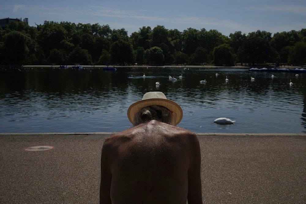 A man sits in the sun at a park in London as parts of the United Kingdom face a heat wave Monday, Aug. 11, 2025. (AP Photo/Kin Cheung)
