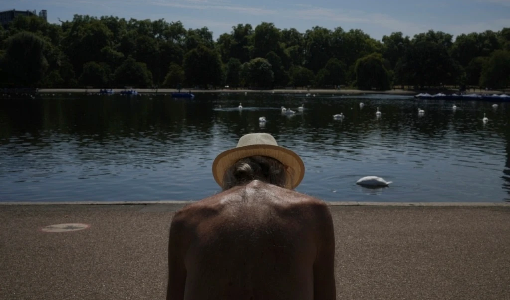 A man sits in the sun at a park in London as parts of the United Kingdom face a heat wave Monday, Aug. 11, 2025. (AP Photo/Kin Cheung)