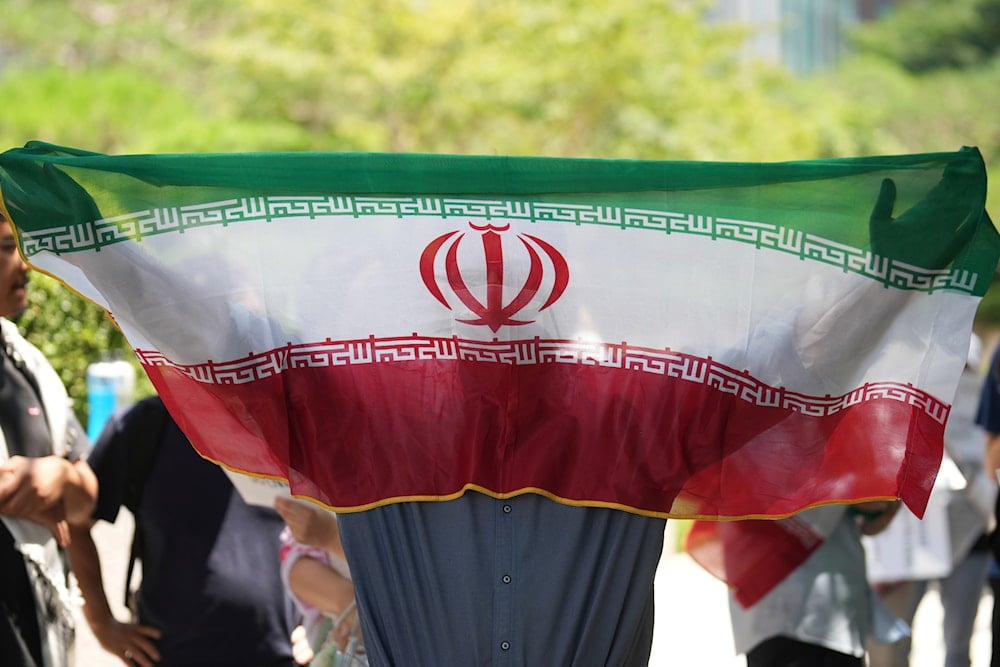 A man holds an Iranian flag during a rally demanding to stop the war between Israel and Iran, in Seoul, South Korea, Sunday, June 22, 2025 (AP)