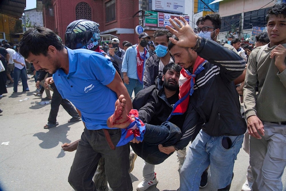 An injured protester is taken to hospital by his friends during a protest in front of the parliament building in Kathmandu, Nepal, Monday, Sept. 8, 2025. (AP Photo/Niranjan Shrestha)